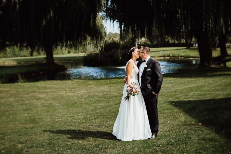 Das Brautpaar küsst sich während eines Hochzeitsfotoshootings auf einem Golfplatz in Ingolstadt