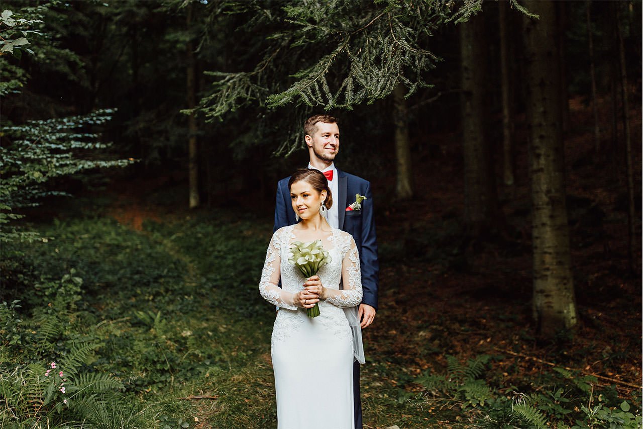 Schöne Braut mit Hochzeit Bouquet von Lilien und Bräutigam während der Porträtfotografie in den Wäldern. 