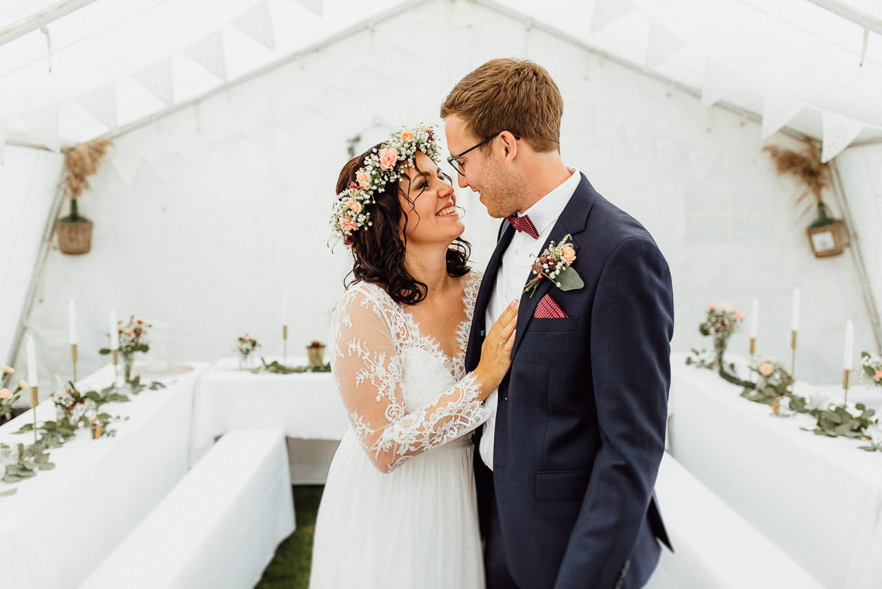Boho-Braut und Bräutigam schauen sich im Zelt vor der Hochzeitsfeier in die Augen
