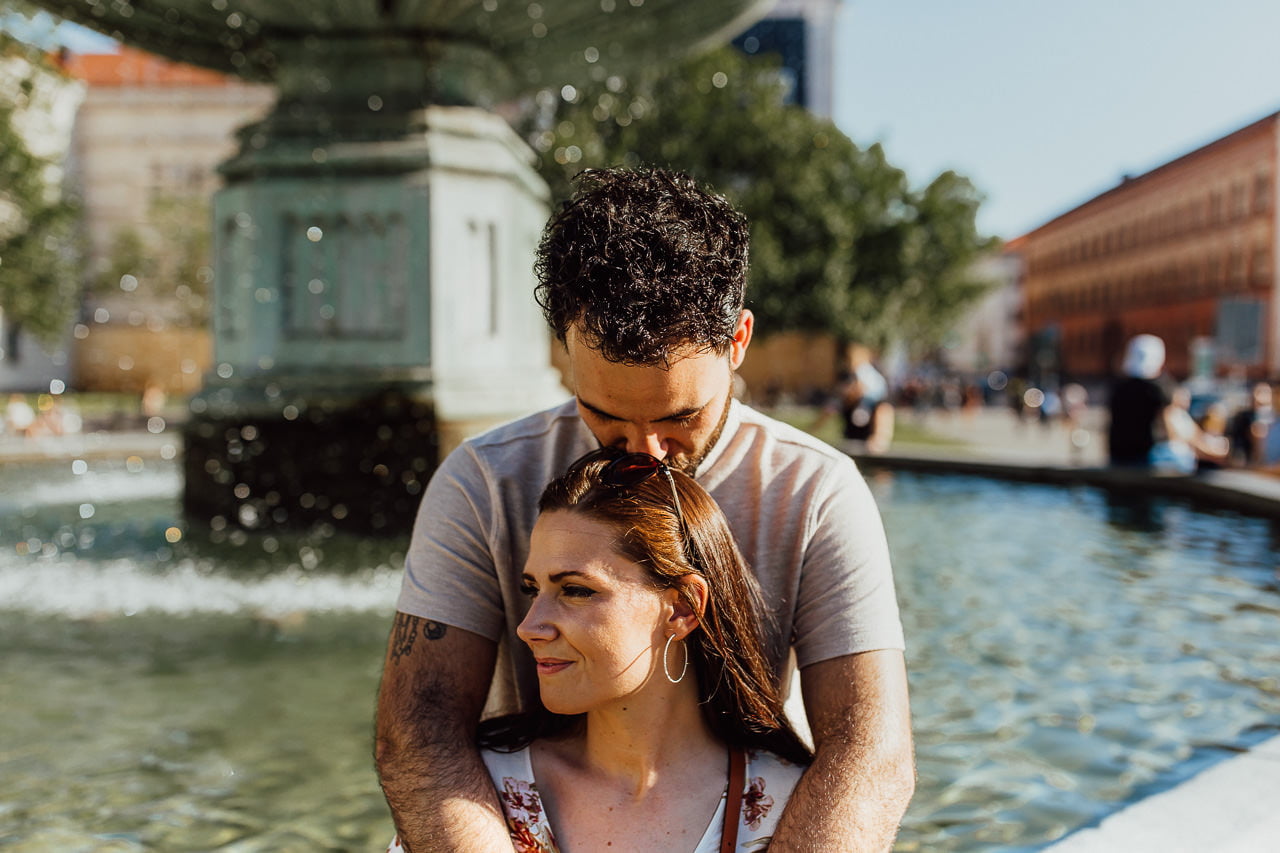 Paar sitzt auf einem Springbrunnen beim Pärchenshooting in München