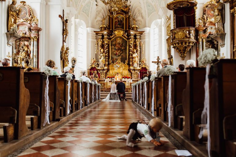 Das Brautpaar vor dem Altar und ein kleines Kind bei einer kirchlichen Trauung in München