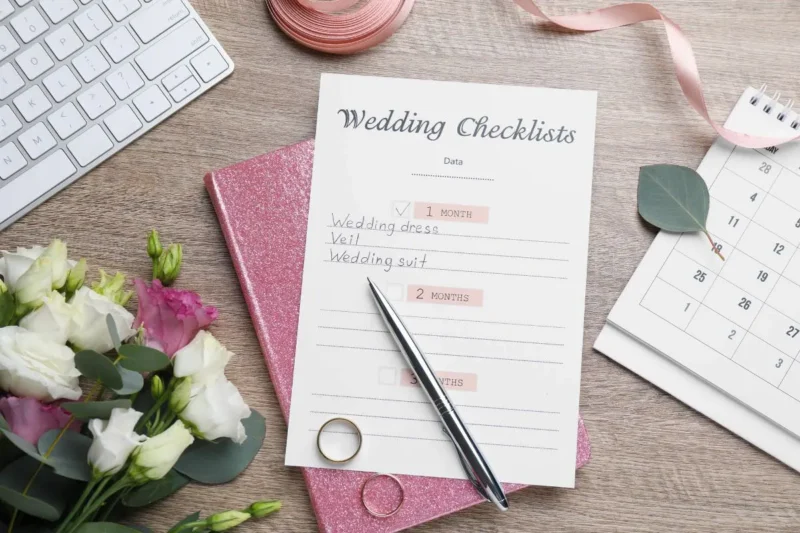Hochzeitscheckliste in Bearbeitung mit Stift und Eheringen - sorgfältige Planung gemäß der Checkliste Hochzeit.