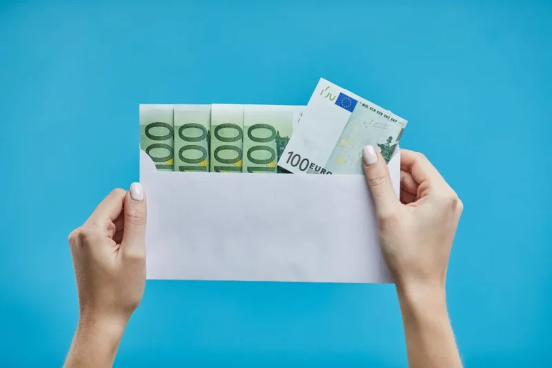 Hand hält Hochzeitskarte mit Geldscheinen als Geschenk
