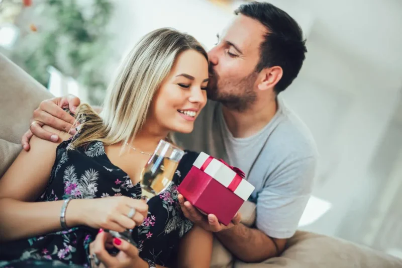 Paar feiert den 10. Hochzeitstag (Rosenhochzeit) – Mann überreicht Frau Geschenk.