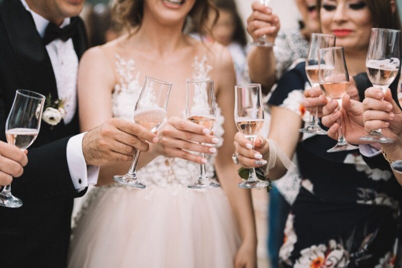Das Hochzeitspaar, umgeben von festlichen Gästen, stößt mit Champagner auf den 15. Hochzeitstag an.
