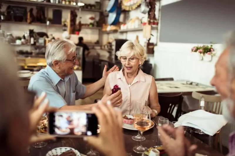 Paar feiert den 45. Hochzeitstag (Messinghochzeit) – Mann überreicht Frau Geschenk, sie ist während des Abendessens überrascht.