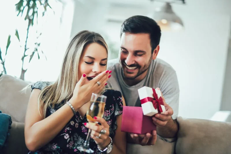 Überraschung zum 5. Hochzeitstag: Frau öffnet liebevoll verpacktes Geschenk.