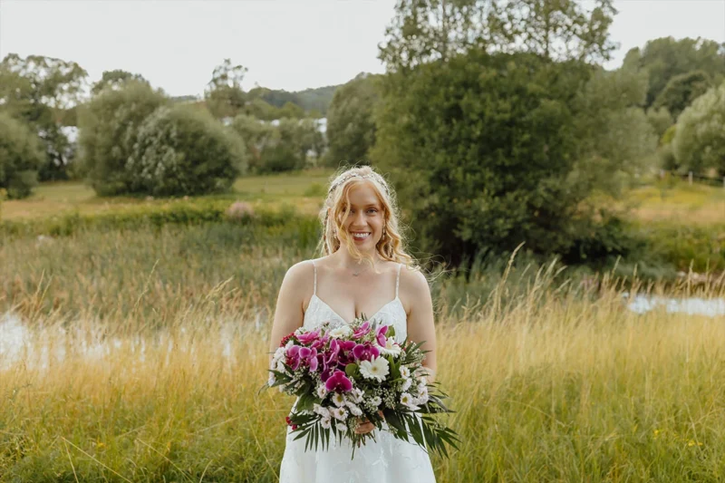 Porträt der strahlenden Braut in ihrer weißen Hochzeitsrobe mit Blumenstrauß. Fotoaufgaben Hochzeit für zeitlose Erinnerungen.