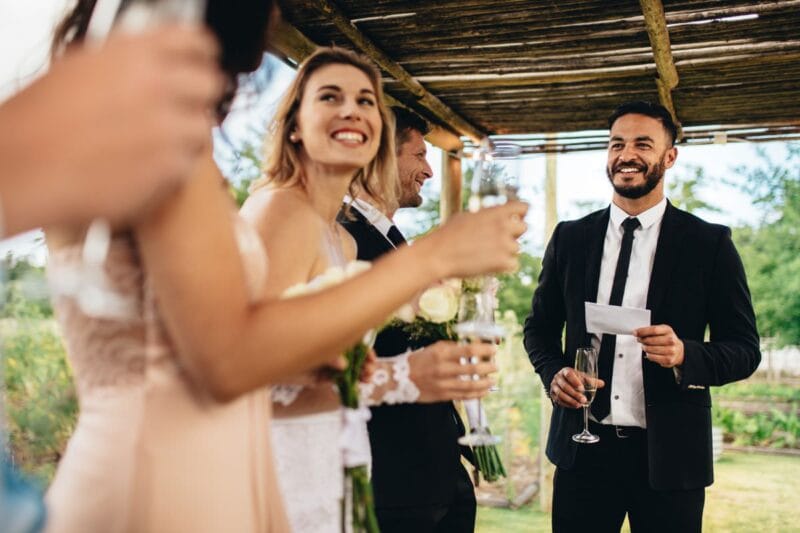 Gäste und Trauzeugen stoßen mit Champagner an und lesen eine amüsante Geschichte aus dem Leben des Brautpaares.