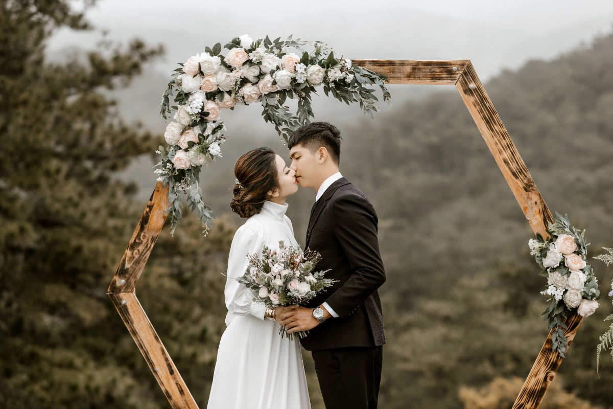 16. Hochzeitstag - Saphirhochzeit. Bedeutung und Geschenkideen. 1 Romantisches Bild einer jungen Braut, die ihren Brautstrauß hält und ihren Bräutigam zum Kuss umarmt, um die Lederhochzeit zu feiern.