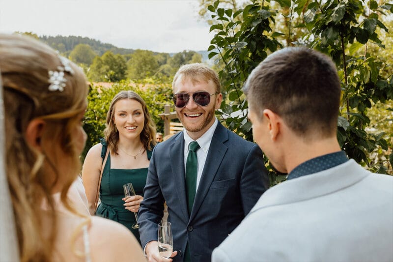 Ein lächelnder Mann übermittelt herzliche Glückwünsche an das Brautpaar am Hochzeitstag.
