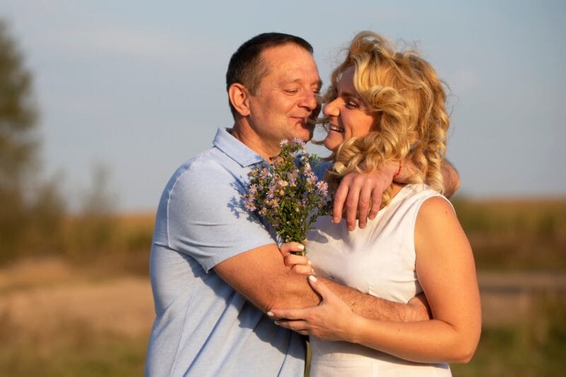 Silberhochzeit: Ein Mann überreicht seiner Frau einen Strauß wilder Blumen auf einer sonnigen Waldlichtung, um ihre 25 Jahre währende Ehe zu feiern.
