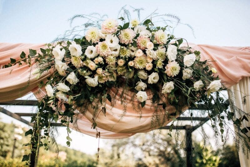 Ein Kränzen Hochzeit schmückt die Kulisse einer Outdoor-Hochzeit.