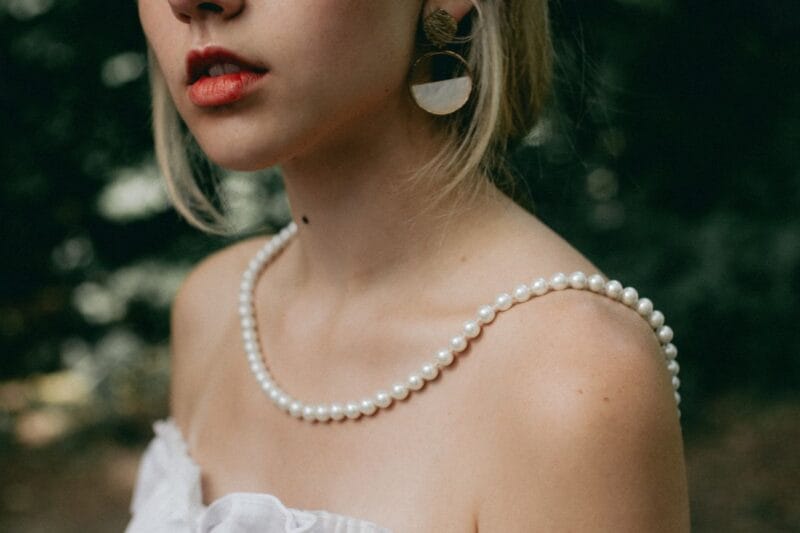 Eine strahlende Braut mit einer eleganten Perlenkette um den Hals für eine zauberhafte Perlenhochzeit.