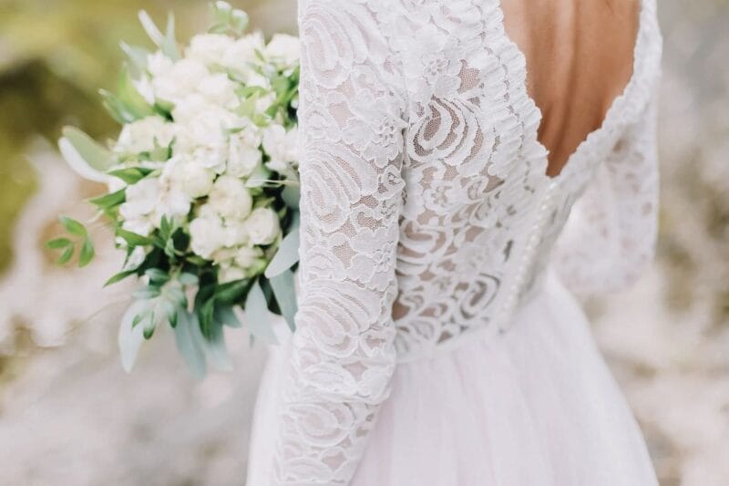 Eine Braut in ihrem Hochzeitskleid hält einen Brautstrauß aus Blumen, bereit, ihr Brautkleid nach der Hochzeit zu spenden.