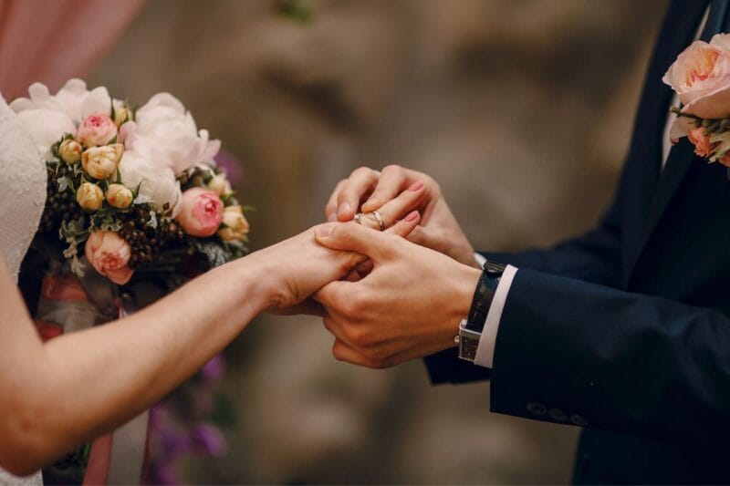 Männliche Hände legen einen Ehering auf eine weibliche Hand - welche Hand ist die Richtige?