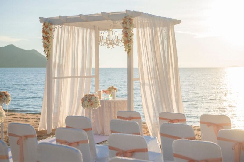 Ein liebevoll dekorierter Strandbereich ist bereit für eine romantische Hochzeit im Freien.