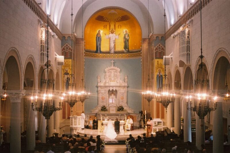Ein festlich geschmückter Kirchenraum ist gefüllt mit Hochzeitsgästen während einer kirchlichen Trauung ohne Standesamt.