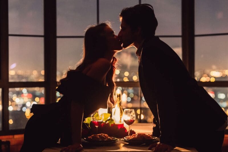Ein verliebtes Paar genießt eine intime Candle-Light-Dinner-Atmosphäre und küsst sich leidenschaftlich.