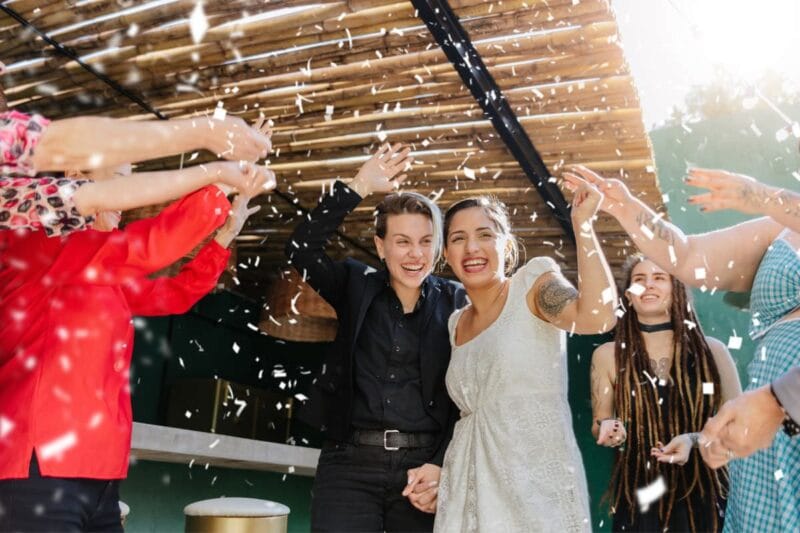 Ein Brautpaar und ihre Hochzeitsgäste präsentieren sich in legerer Hochzeitskleidung.