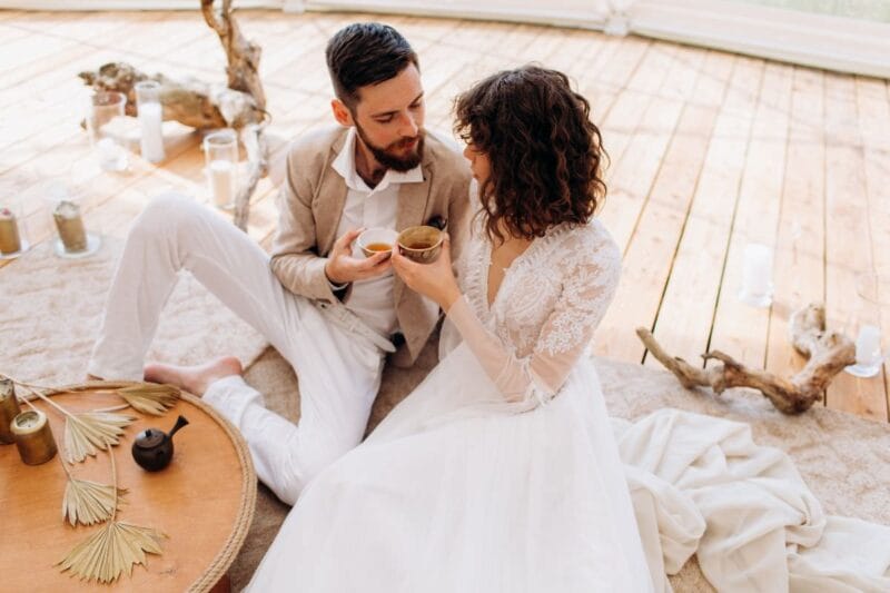 Braut und Bräutigam trinken Tee, die Braut trägt ein elegantes Brautkleid mit Ärmeln.