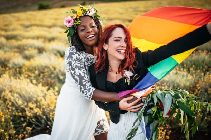 Brautpaar bei der Hochzeit mit Regenbogenflagge und Blumenkronen im Haar, Haarkranz Hochzeit.