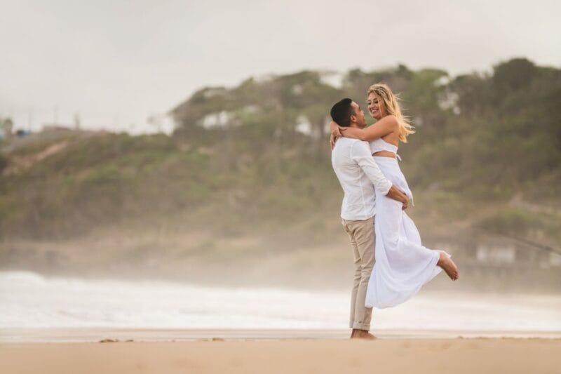 Die Braut trägt einen Hochzeit Jumpsuit beim Spaziergang am Strand.