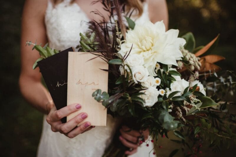 Die Braut hält einen Brautstrauß und Hochzeitsbücher in der Hand, perfekt für die Erinnerungen an den Hochzeitstag.