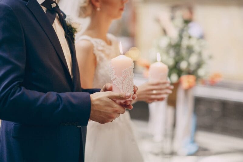 Nahaufnahme des Brautpaares mit eleganten Hochzeitskerzen in der Kirche.