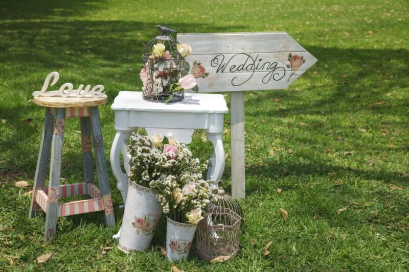 Eine Wegweiser-Tafel mit den Worten "Wedding, Love" und Blumenarrangements zeigt den Ort des Kindsbaums.