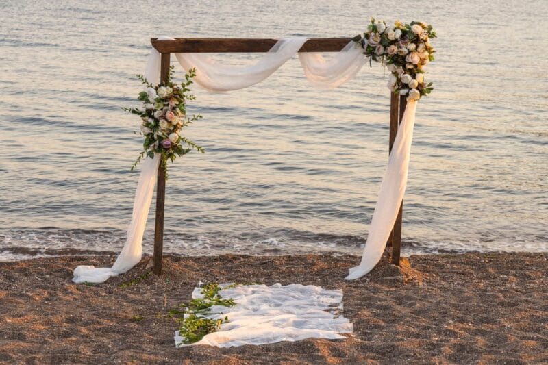 Hochzeitsbogen am Strand für eine traumhafte Sylt Hochzeit bei Sonnenuntergang.