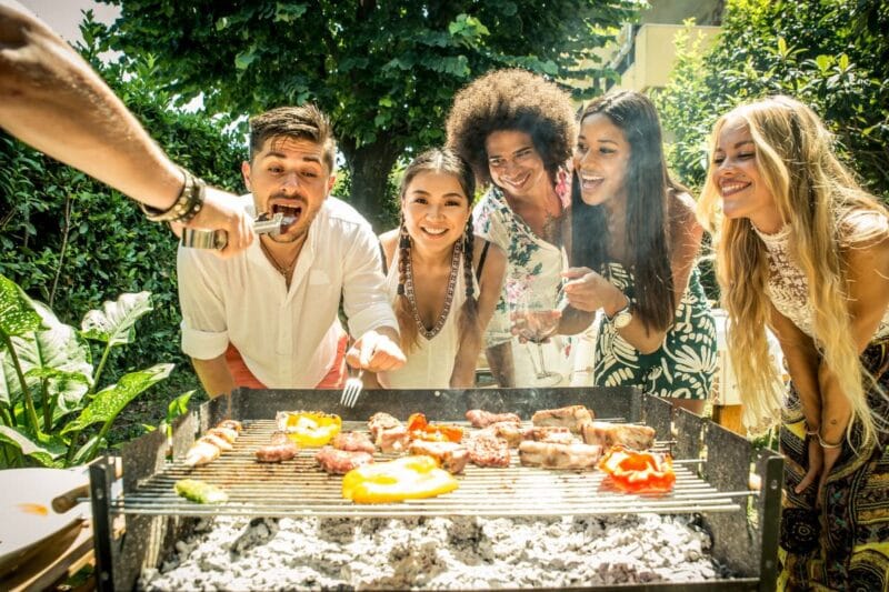 Grillen Hochzeit - Gruppe von Freunden genießt gegrilltes Essen bei einer Hochzeitsfeier im Freien.