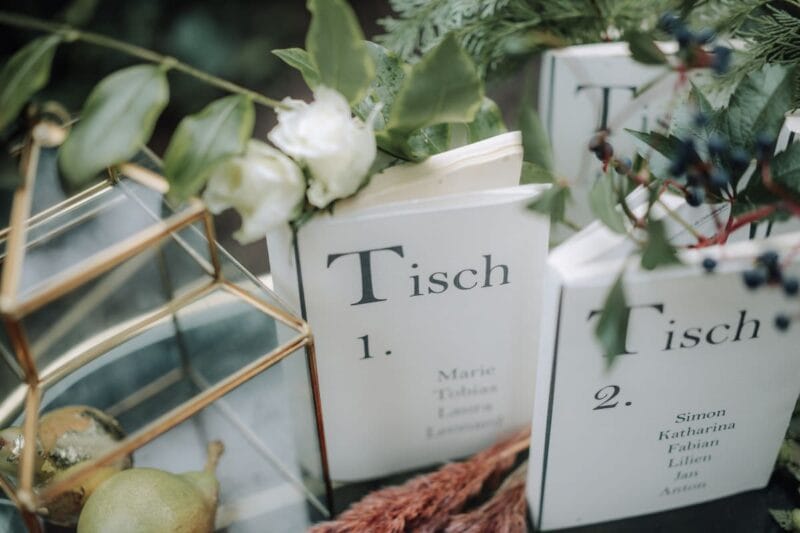 Zwei wunderschöne Hochzeitstischnummern in Form von blumengeschmückten Büchern zieren den Tisch.