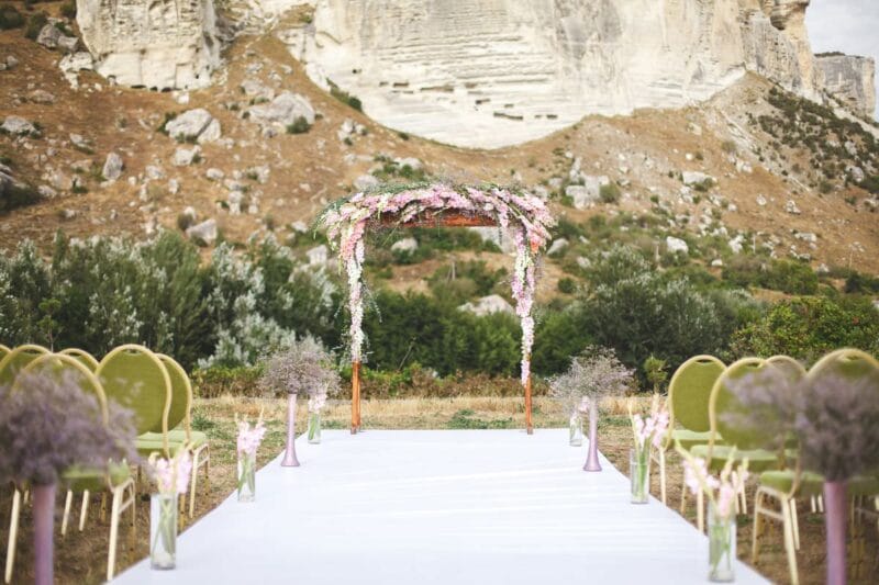 Romantischer Traubogen Hochzeit mit Blumenarrangement vor beeindruckender Felskulisse, ideal für eine Outdoor-Hochzeit.