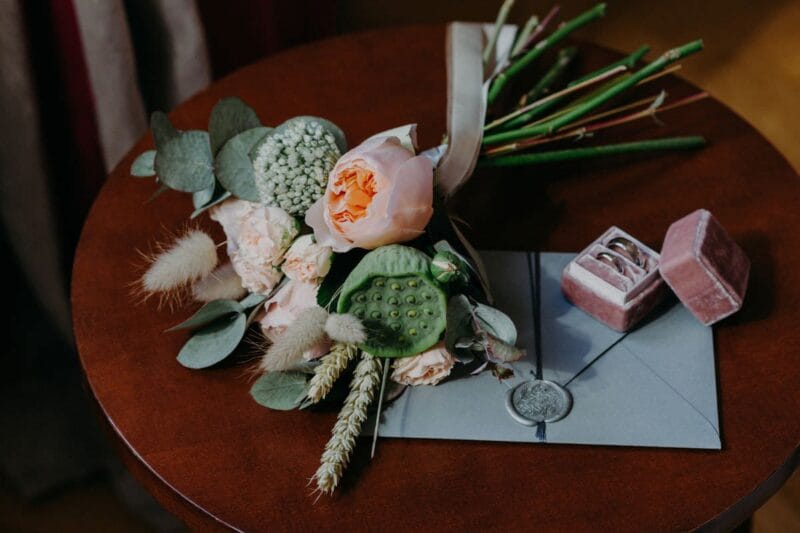 Stilvolle Einladungskarten zur goldenen Hochzeit neben Blumenstrauß und Eheringen